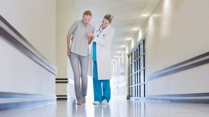médica ayudando a una paciente a caminar por el pasillo