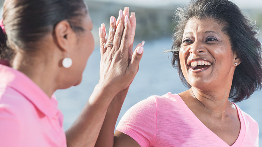 Dos mujeres afroamericanas vestidas de rosa chocan los cinco