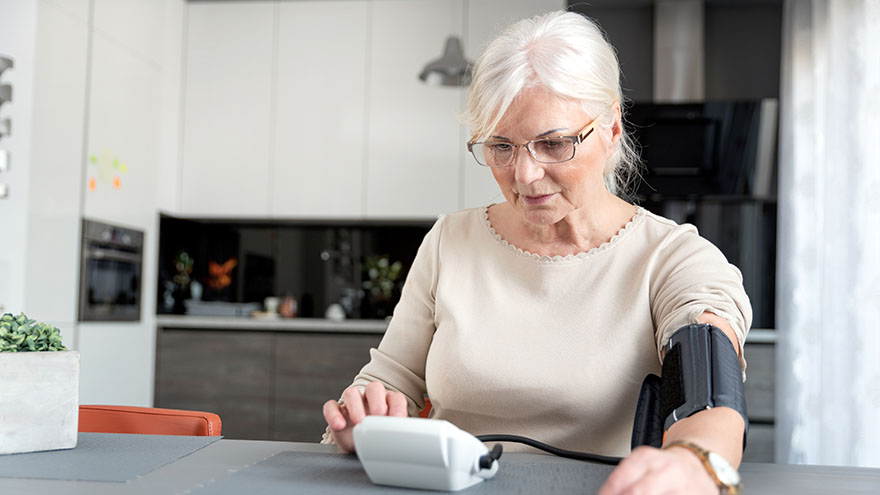 Mujer mayor controlándose la presión arterial en su hogar