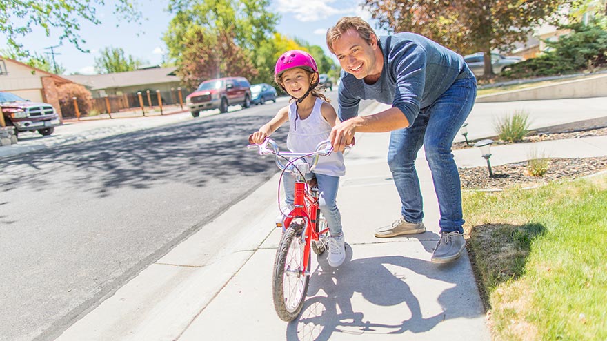 Dad teaching daughter how to ride a bike