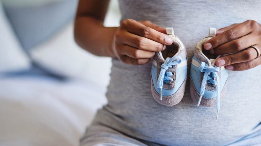 Mujer embarazada sosteniendo zapatitos de bebé contra su abdomen